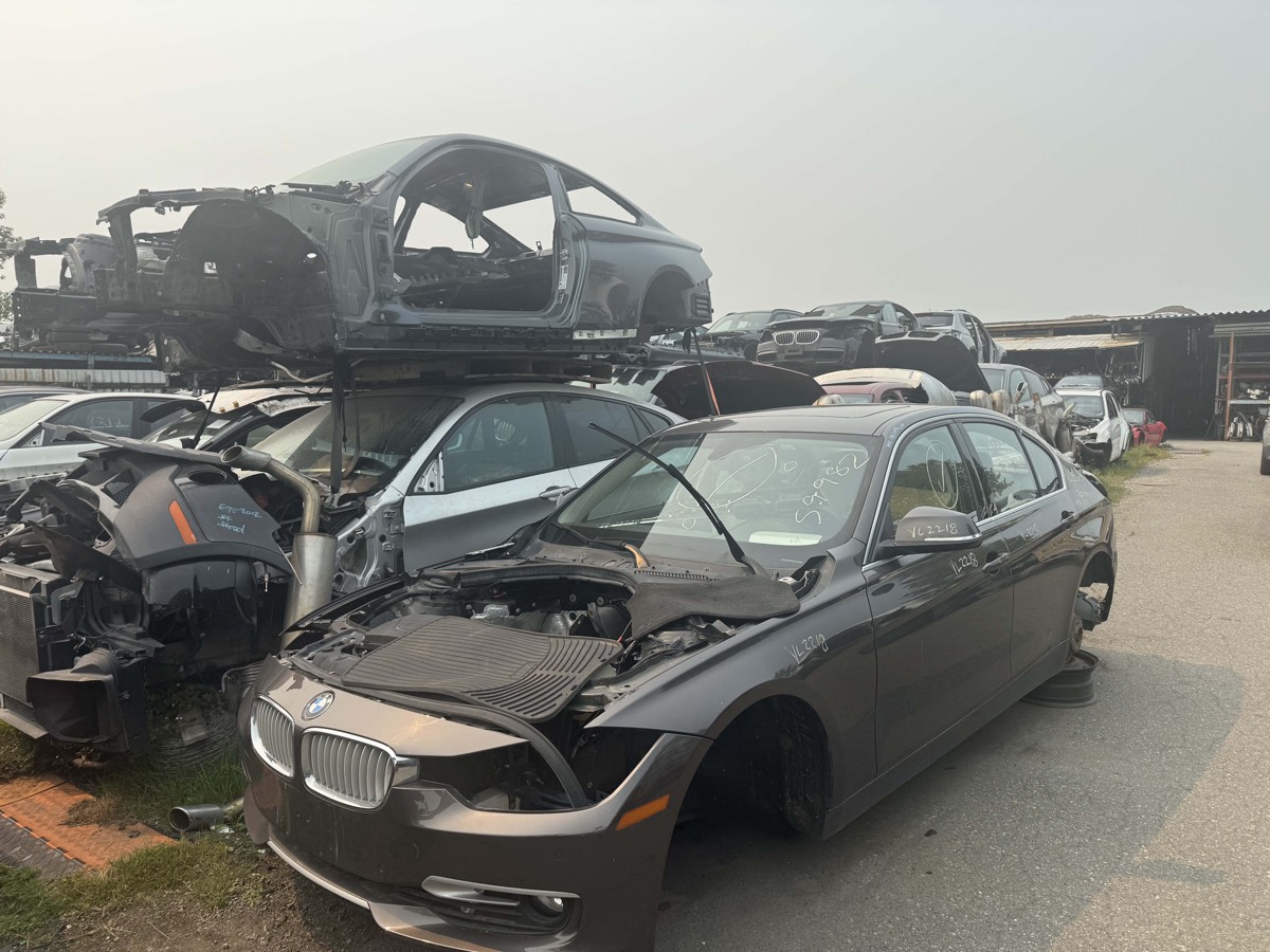 Stripped BMW body shells stacked above a 3 Series awaiting dismantling.