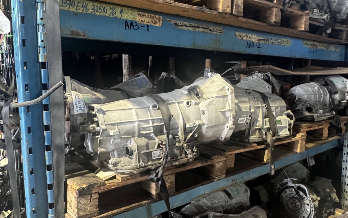Used BMW transmissions and drivetrain parts on warehouse racking.