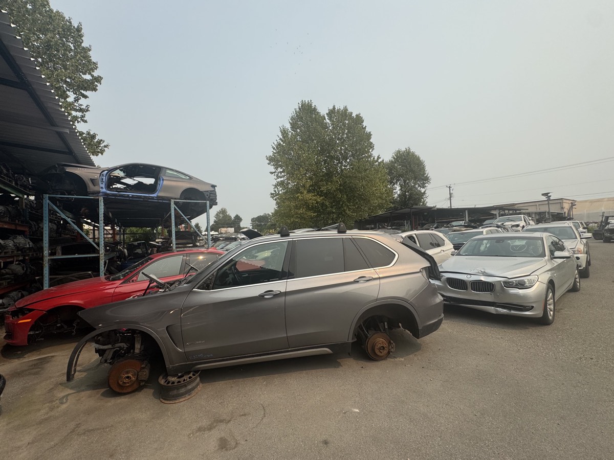 A wide view of the Affordable Auto Parts yard in Burnaby, BC, with BMWs and stacked body shells awaiting dismantling.